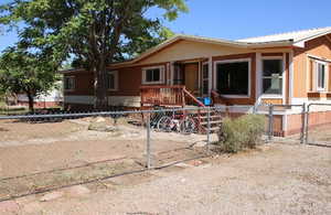 Manufactured / mobile home featuring a fenced front yard, a gate, a metal roof, and a wooden deck
