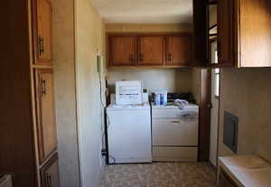 Laundry room featuring cabinet space, washer and clothes dryer, light floors, and a textured ceiling
