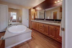 Ensuite bathroom with a stall shower, soaking tub, double vanities, large walk-in closet, and lots of storage