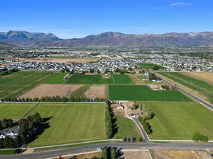 Aerial view of property and surrounding area with a mountain backdrop, rural landscape, and large plots for crops