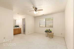 Unfurnished bedroom featuring light colored carpet, a textured ceiling, ceiling fan, and ensuite bathroom
