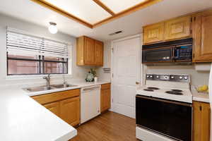 Kitchen featuring electric range, light countertops, black microwave, dishwasher, and light wood-type flooring