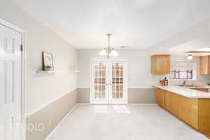 Unfurnished dining area with a textured ceiling, a chandelier, and light carpet