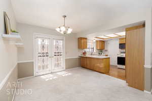 Kitchen featuring light countertops, light carpet, electric stove, a peninsula, and black microwave