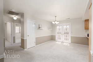 Unfurnished dining area with a chandelier and light colored carpet