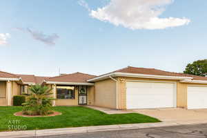 View of front of home featuring a front yard, brick siding, a garage, and driveway