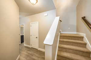 Staircase featuring baseboards and laminate floors and half bath