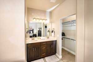 Ensuite primary bathroom featuring double vanity and a walk in closet