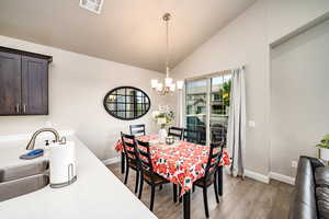 Dining space featuring lofted ceiling, light wood-type flooring, and a chandelier