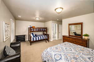Bedroom 2 featuring light colored carpet, connected bathroom, and a textured ceiling