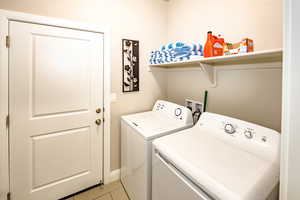 Washroom with light tile patterned flooring and separate washer and dryer