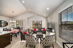 Living room featuring laminate finished floors, a chandelier, recessed lighting, and vaulted ceiling