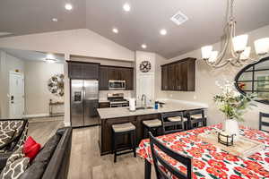 Kitchen and dining room area featuring laminate flooring, a chandelier, high vaulted ceiling, and recessed lighting