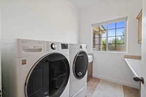 Laundry area featuring light tile patterned floors, separate washer and dryer, and cabinet space