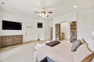 Bedroom featuring light colored carpet, arched walkways, recessed lighting, ceiling fan, and ensuite bathroom