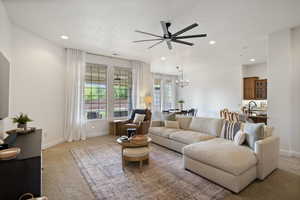 Living room with light colored carpet, recessed lighting, ceiling fan, and a chandelier