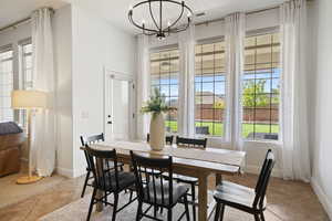 Dining space featuring healthy amount of natural light, light tile patterned flooring, and a chandelier