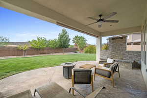 Fenced backyard with a patio area, ceiling fan, and an outdoor living space with a fire pit