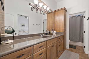 Bathroom with vanity, light tile patterned floors, ensuite bath, curtained shower, and a chandelier