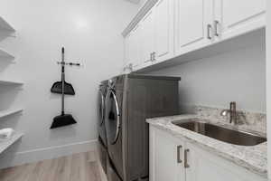 Laundry area with light wood finished floors, independent washer and dryer, and cabinet space
