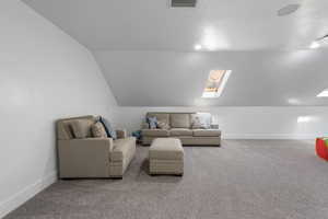 Living area featuring a skylight, carpet flooring, a textured ceiling, and lofted ceiling