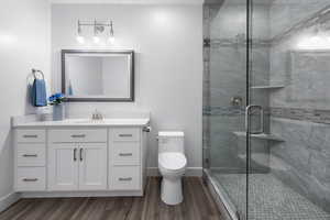 Full bathroom with vanity, a stall shower, and dark wood finished floors
