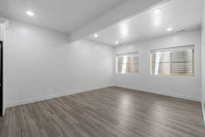 Empty room with light wood-style floors, beam ceiling, and recessed lighting