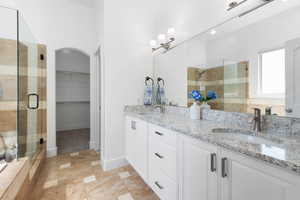Bathroom with a shower stall, double vanity, and a walk in closet