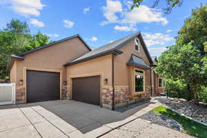 View of front facade with stone siding, stucco siding, an attached garage, concrete driveway, and roof with shingles