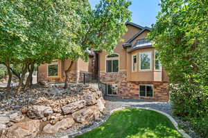 Back of property featuring stone siding and stucco siding