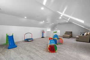 Playroom featuring a skylight, carpet, lofted ceiling, a textured ceiling, and recessed lighting