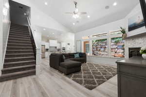 Living area with stairs, recessed lighting, light wood-type flooring, ceiling fan, and high vaulted ceiling