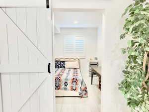 Bedroom featuring a barn door, light wood-type flooring, and recessed lighting