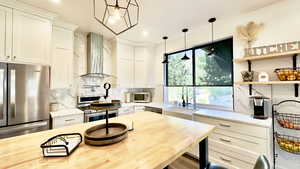 Kitchen featuring wooden counters, tasteful backsplash, appliances with stainless steel finishes, wall chimney range hood, and recessed lighting