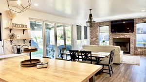 Dining area featuring a brick fireplace, brick wall, healthy amount of natural light, dark wood-style flooring, and recessed lighting