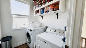 Laundry area with dark wood finished floors and washer and clothes dryer