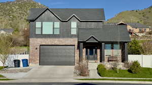 View of front of house with covered porch, concrete driveway, a garage, a mountain view, and brick siding