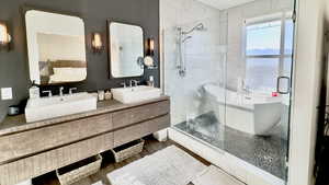 Bathroom featuring a shower stall, a soaking tub, double vanity, and wood finished floors