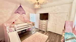 Bedroom with dark wood-type flooring, a closet, and a chandelier