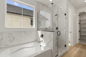 Full bath with a garden tub, a marble finish shower, light wood-style floors, a walk in closet, and recessed lighting