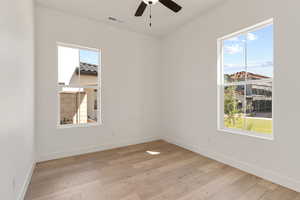 Empty room with plenty of natural light, light wood-type flooring, and a ceiling fan