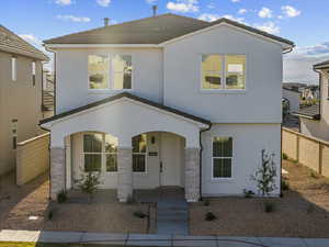 View of front of house with stucco siding, covered porch, and stone siding