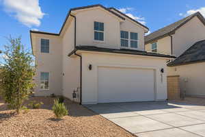 View of front of house with an attached garage, stucco siding, concrete driveway, and a tiled roof