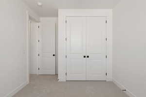 Unfurnished bedroom with light colored carpet and a closet