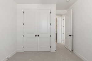 Unfurnished bedroom featuring light carpet and a closet