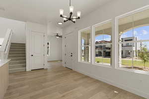 Unfurnished dining area with stairs, light wood-style floors, a chandelier, and a ceiling fan