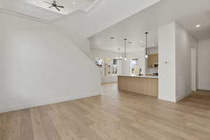 Unfurnished living room featuring light wood finished floors, a ceiling fan, a chandelier, and recessed lighting