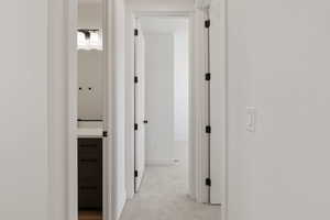 Corridor featuring light colored carpet