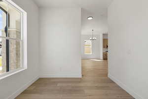 Spare room with light wood finished floors and a chandelier