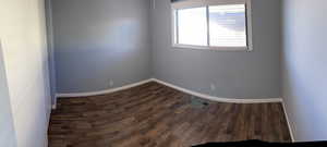Unfurnished room featuring dark wood finished floors and baseboards